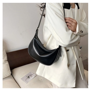 Detail of a black PU crescent underarm bag worn by a model in a white blazer jacket