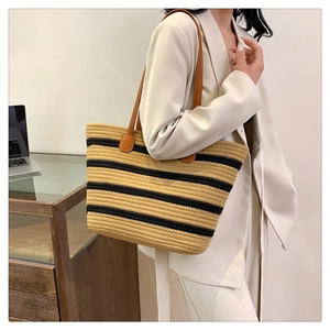 Detail of woven cotton rope tote with black stripes and brown leather shoulder straps