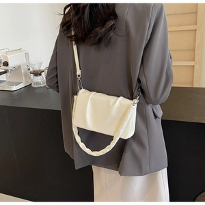 Detail of a creamy white ruched shoulder bag with textured leather and a thick pleated handle