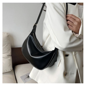 Close-up of black PU hobo bag texture and zipper detail worn with white blazer