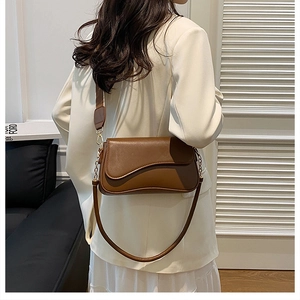 Détail d'un sac bandoulière en cuir marron avec un design de rabat incurvé en forme de vague