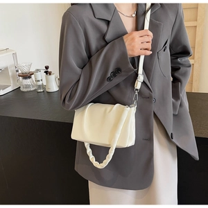 Chic creamy white pleated crossbody bag shown with professional coffee shop background