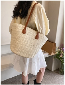 Detail showing the large capacity woven straw tote bag with brown handles and natural texture