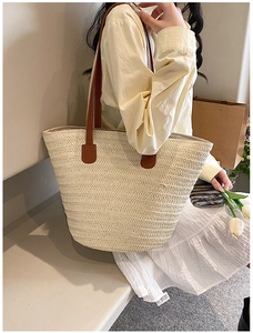 Close-up of beige woven tote bag featuring natural texture and brown leather straps