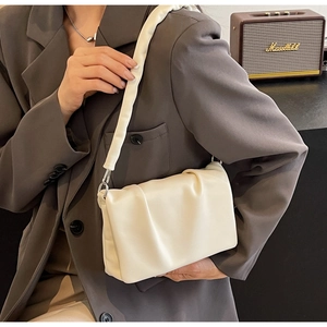 Close-up of creamy white ruched shoulder bag texture with soft leather and silver buckles