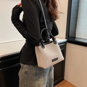 Chic beige canvas bucket bag with black leather trim and knotted handle for women