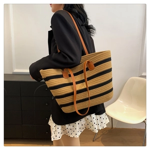 Close-up of woven striped cotton tote bag featuring premium brown leather shoulder straps