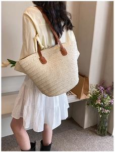 Detail of hand-woven straw tote bag with brown leather handles and natural texture
