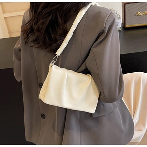 Close-up of pleated cream shoulder bag with wide strap and silver metal buckle details