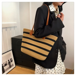 Detail view of woven cotton stripe tote bag with brown leather handles worn on shoulder