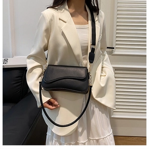 Détail de la sacoche en cuir noir mat avec boucle dorée et bandoulière large