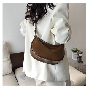 Detailed view of brown PU leather crescent shoulder bag with soft pleated design and texture
