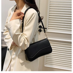 Détail du sac bandoulière noir avec rabat ondulé et chaîne dorée sur mannequin