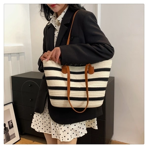 Close-up of a striped woven cotton tote bag with brown leather handles for beach or commute
