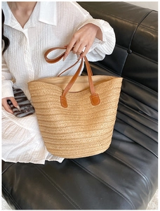 Detail of woven straw tote bag with brown leather handles on a white dress model