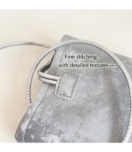 Detail of silver brushed leather phone bag with tight stitching and spiral metal strap
