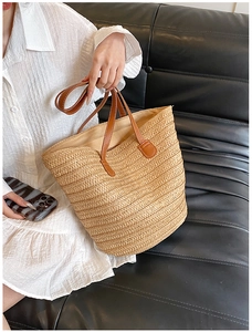 Detailed view of the woven texture and brown leather strap on a beige summer tote bag
