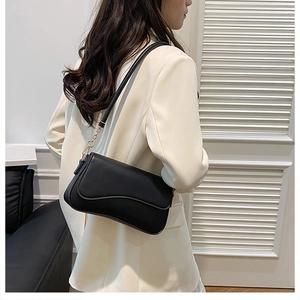 Détail du sac bandoulière minimaliste en cuir noir avec élégante bandoulière chaîne dorée