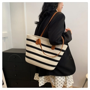 Detailed shot of large striped woven tote bag with premium brown leather straps on model