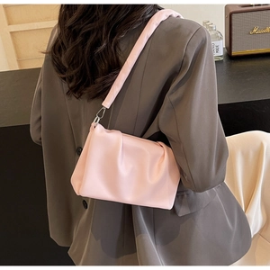 Detailed side view of pink pleated cloud bag with wide shoulder strap on a female model
