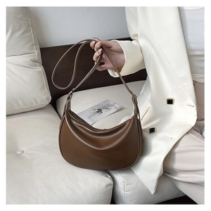 Detail of a brown PU leather hobo bag with pleated texture and thin shoulder strap