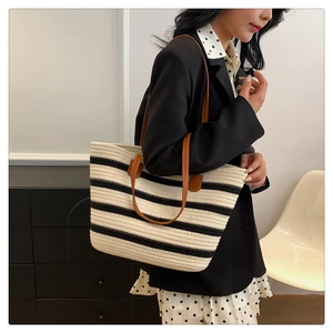 Detail of woven black and white striped tote bag with brown leather shoulder straps