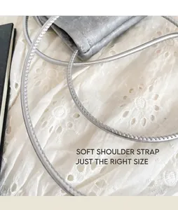 Detail of silver metallic crossbody bag strap featuring fine stitching and soft texture