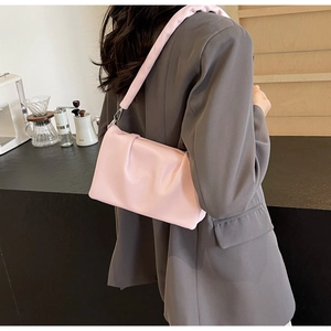 Close-up of soft pink pleated cloud bag with elegant shoulder strap and metal buckle