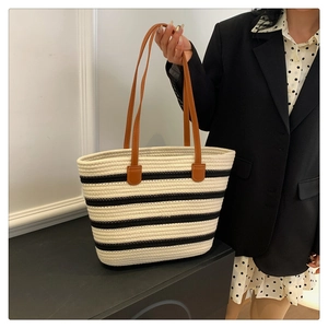 Detail of woven striped tote bag with contrast black stripes and brown leather straps