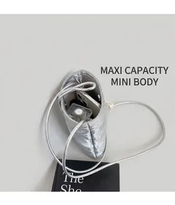 Detail view of silver mini crossbody bag showing interior space for phone and perfume