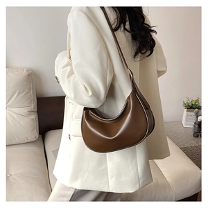 Detail of dark brown PU leather half moon bag worn with a white oversized blazer