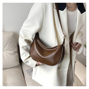 Brown PU leather crescent shoulder bag styled with a white blazer for a chic professional look