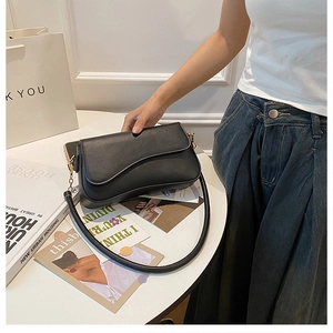 Détail du sac selle noir en cuir mat avec design incurvé élégant et boucle dorée chic