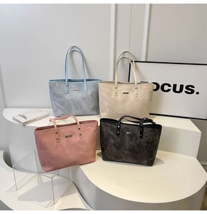 Four vintage tote bags in assorted colors displayed on minimalist geometric stands