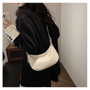Close-up of cream PU leather crescent bag with adjustable strap and metal hardware