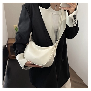 Close-up of a cream PU leather crescent bag featuring a smooth finish and adjustable strap