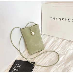 Detail view of sage green suede phone bag featuring a large pearl closure on white lace
