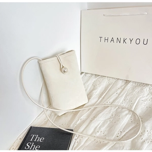 Detail of a mini beige crossbody phone bag featuring a large pearl clasp and thin rope strap