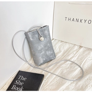 Detail of grey crossbody mini phone bag featuring a large pearl clasp and silver strap