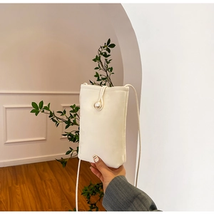Minimalist white phone bag featuring a large pearl clasp and slender crossbody strap
