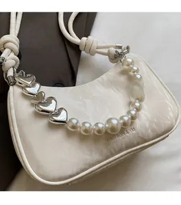 Detail of white moon bag featuring pearl strap and heart-shaped metal charms