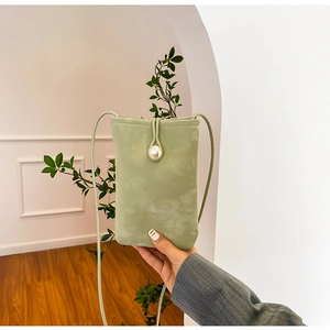 Close-up of light green suede phone bag featuring a white pearl closure detail