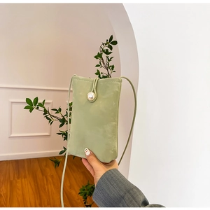 Light green mini crossbody phone bag with large pearl clasp and suede texture details