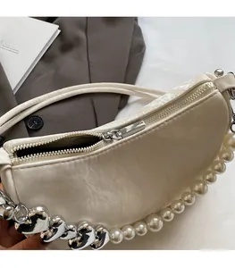 Detailed macro view of the smooth silver zipper on a creamy white underarm bag