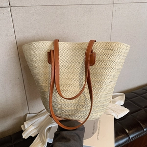Beige straw tote bag with V-weave texture and brown leather straps for summer beach travel