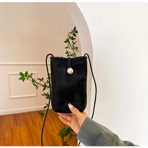 Detail of black velvet phone bag featuring a pearl clasp and minimalist rope strap