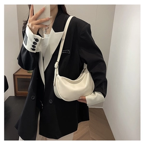 Detailed view of cream PU leather hobo bag worn with black suit for elegant style