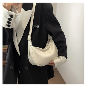 Minimalist cream white PU leather dumpling bag shown on shoulder with stylish blazer