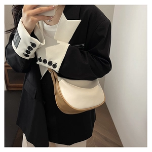 Close-up of stylish cream and camel faux leather crescent moon bag worn by model