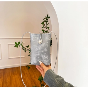 Detail of grey suede mini bag with large pearl closure and silver thin rope strap